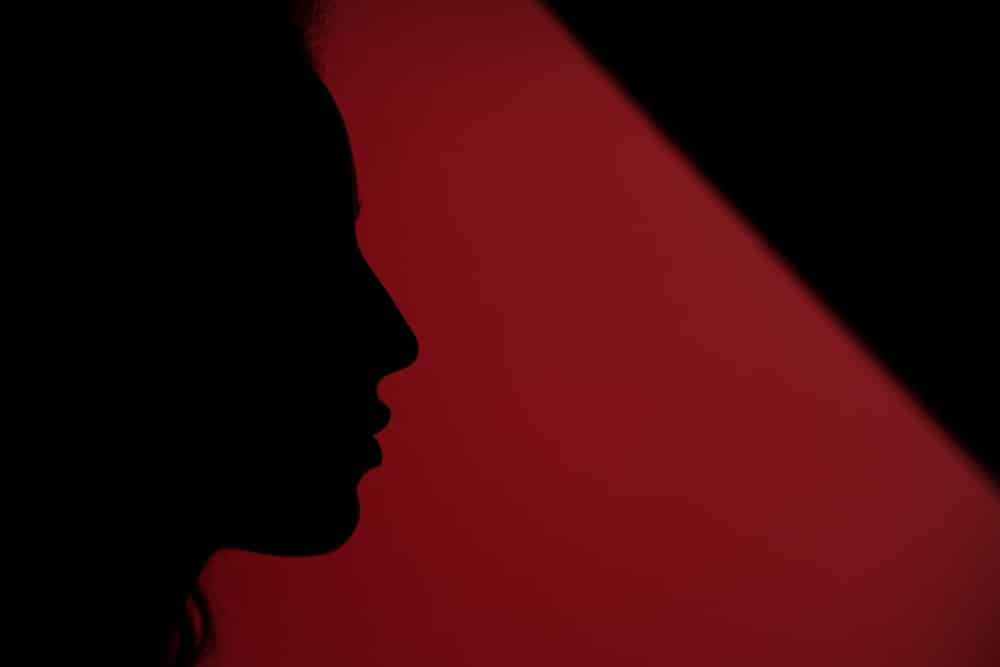 Silhouette of a woman in profile on a red wall