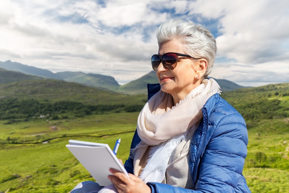 woman over 50 writing her first novel sitting in a field.