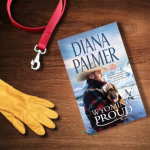 Book Wyoming Proud by Diana Palmer a red dog leash and a leather glove laying on a wooden table