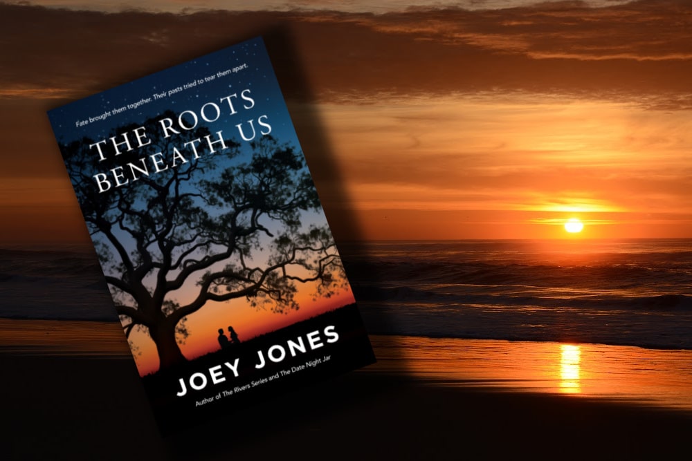 The book The Roots Beneath Us by Joey Jones and a a sunset in the Outer Banks