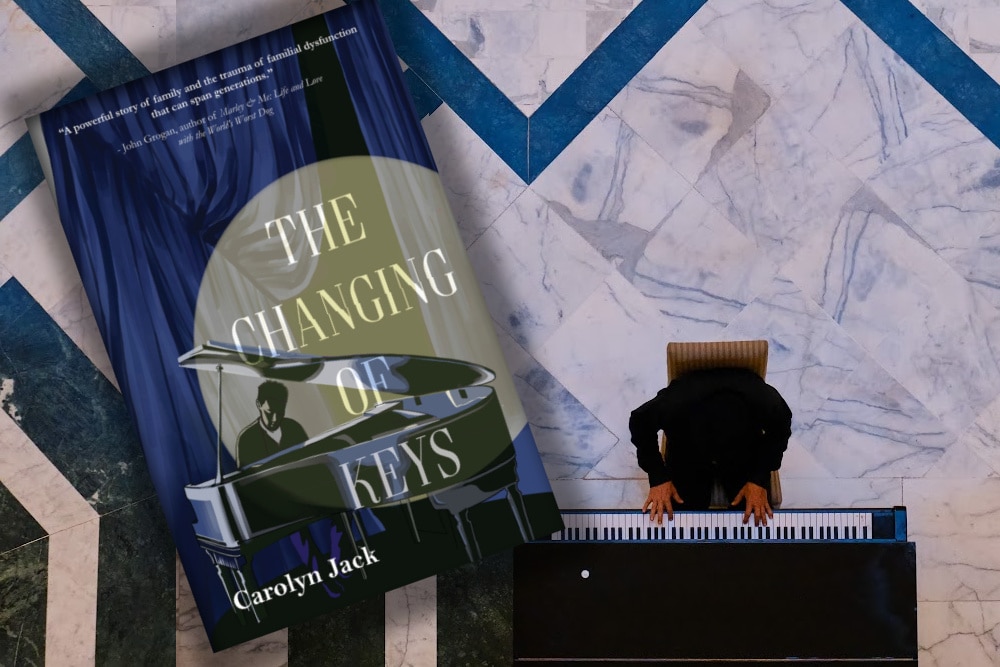 top view of a man on a marble floor playing a piano and the cover of the book The Changing of the Keys overlayed on the side