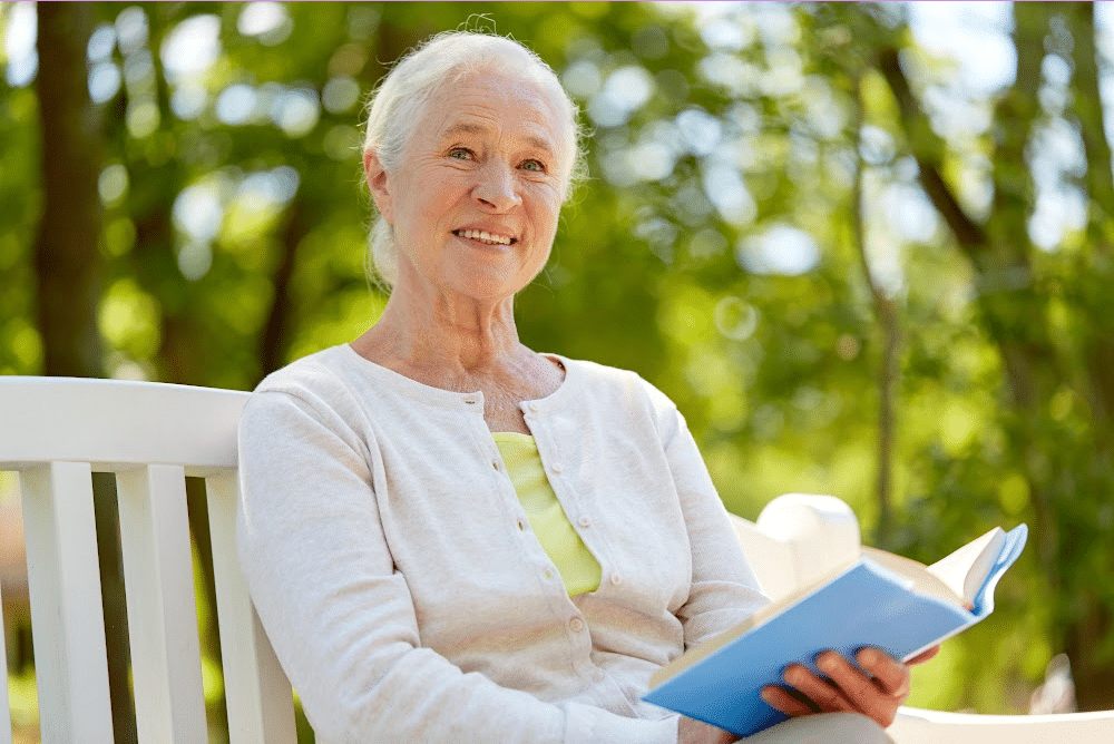 woman over 50 reading a book in a park