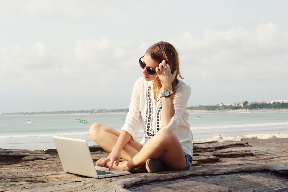 woman writing at the beach on a laptop