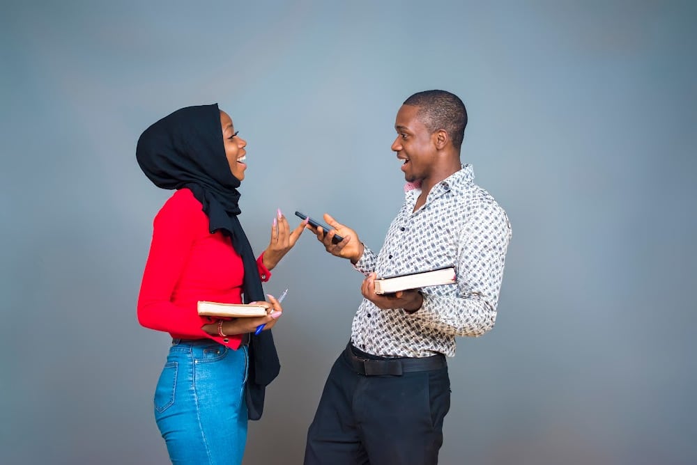 a female writer and a male writer having a conversation and holding their books