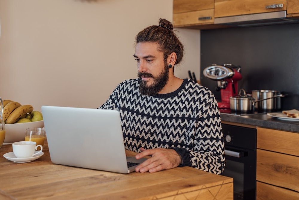 man sitting at a kitchen counter with a laptop
