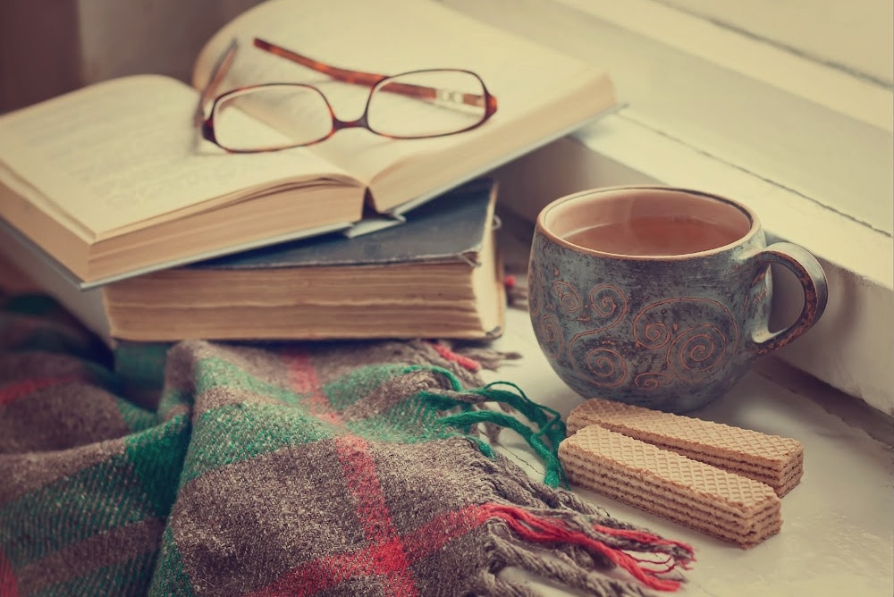 cozy reading nook books, tea, glasses and a snack